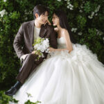 グリーンの前で座った新郎新婦　