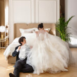 寝室のベット上に座った新婦と新郎のお洒落な前撮り写真’