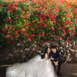 バラの花の前で座った新郎新婦のウェディング写真