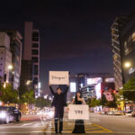 夜の道路の真ん中でプラカードを持った新郎新婦