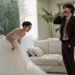 白いソファーと大きな窓のある部屋で微笑み合う新郎新婦