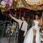 メリーゴーランドに座った新婦とバルーンを持つ新郎